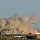A photo of a blue origin rocket taking off with a big cloud of brown smoke.